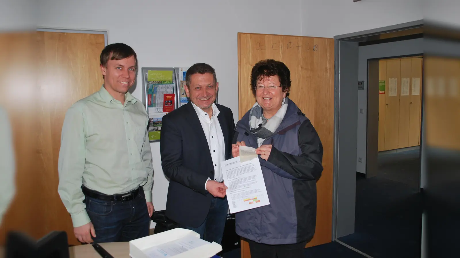 Bürgermeister Korneder begrüßte gemeinsam mit Sebastian Stüwe vom Umweltamt erste Bürgerin, Annemarie Weinberger, die sich das Saatgut im Rathaus abholte. (Foto: privat)