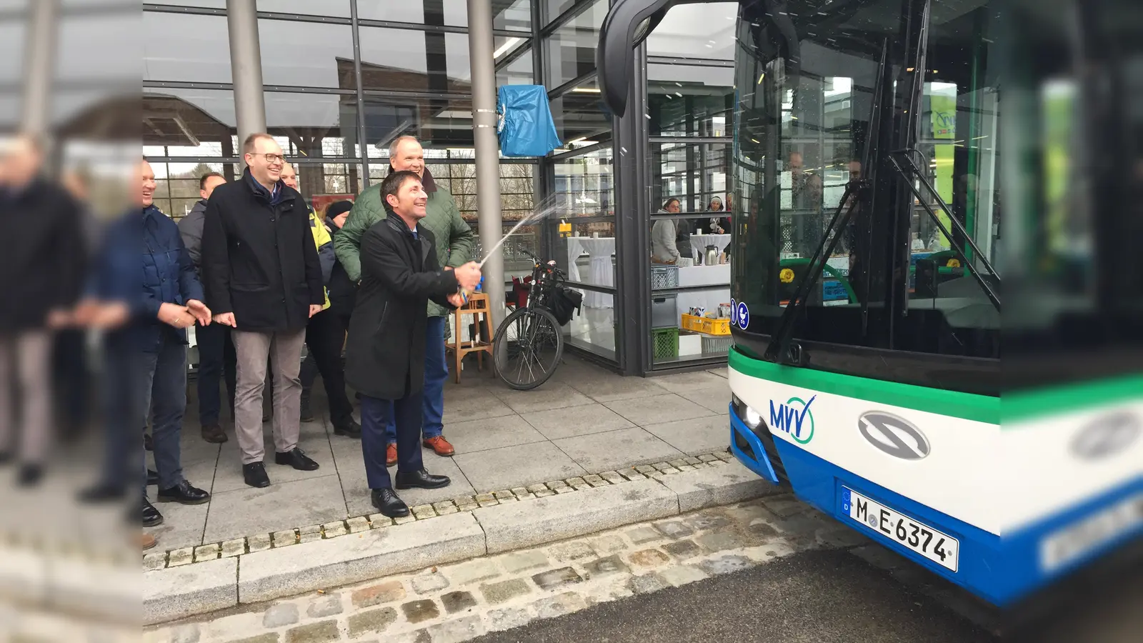 Unterföhrings Erster Bürgermeister Andreas Kemmelmeyer freut sich über die Inbetriebnahme der E-Buslinie 232 und weiht einen der Busse mit einer Sektdusche ein. (Foto: Landratsamt München)