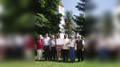 Im Hintergrund die wunderschöne Aubinger Pfarrkirche St. Quirin, für deren Renovierung jetzt die Scheckübergabe stattfand: (von links) die beiden Bäckermeister Richard Mayer senior und junior, Kirchenpfleger Gerhard Fleck, Julia Mayer, Ehefrau des Juniorchefs, Pater Georg sowie Gisela Busch und Anton Fürst von der Projektgruppe „Kirchenrenovierung St. Quirin“. (Foto: Eva Schraft)