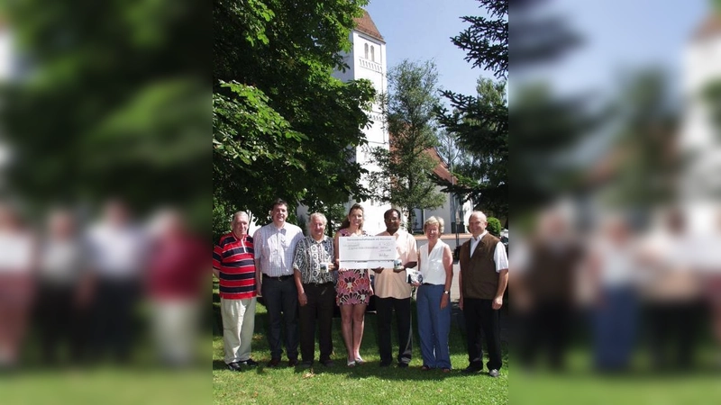 Im Hintergrund die wunderschöne Aubinger Pfarrkirche St. Quirin, für deren Renovierung jetzt die Scheckübergabe stattfand: (von links) die beiden Bäckermeister Richard Mayer senior und junior, Kirchenpfleger Gerhard Fleck, Julia Mayer, Ehefrau des Juniorchefs, Pater Georg sowie Gisela Busch und Anton Fürst von der Projektgruppe „Kirchenrenovierung St. Quirin“. (Foto: Eva Schraft)