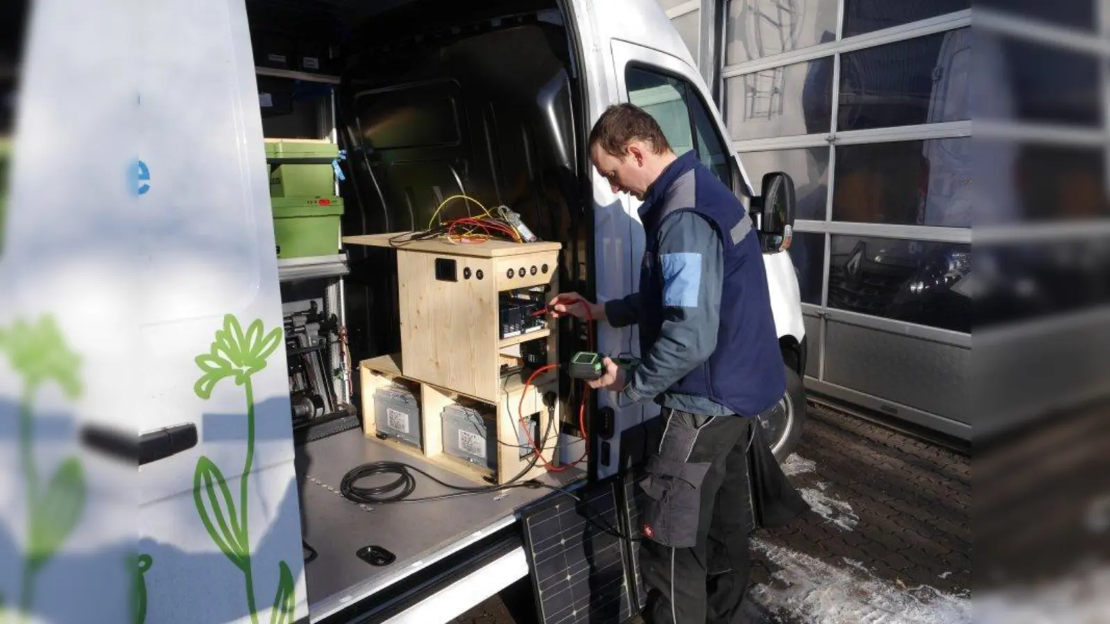 Georg Hauser überprüft die Funktion des Spannungswandlers und der Spannung von der mobilen und festen Solaranlage auf dem Fahrzeugdach. (Foto: Burg Schwaneck)