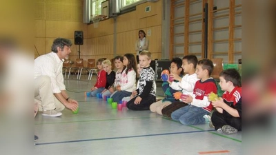 Gilson de Assis vom K.I.D.S.-Projekt zeigt hier mit Erstklässlern, dass nicht unbedingt gleich teure Instrumente nötig sind, um die ersten Percussion-Versuche zu machen. (Foto: Eva Schraft)