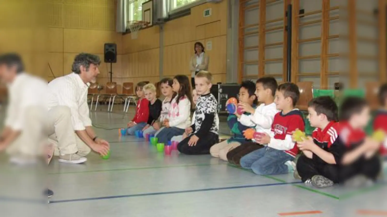 Gilson de Assis vom K.I.D.S.-Projekt zeigt hier mit Erstklässlern, dass nicht unbedingt gleich teure Instrumente nötig sind, um die ersten Percussion-Versuche zu machen. (Foto: Eva Schraft)