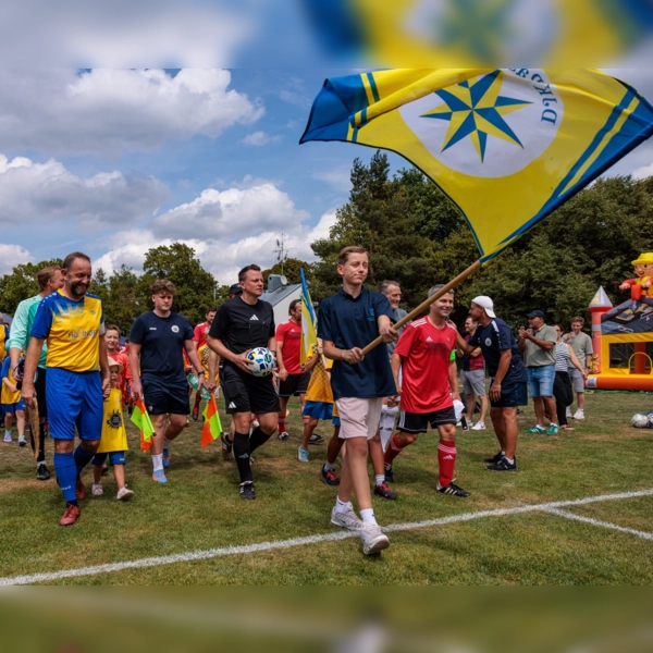 Mit wehender Vereinsfahne auf den Platz: Die DJK Pasing Allstars und der FC Sternstunden beim gemeinsamen Einlauf zum Benefizspiel anlässlich des 70-jährigen Jubiläums der DJK Pasing. (Foto: Christian Riedel/fotografie-riedel.net)