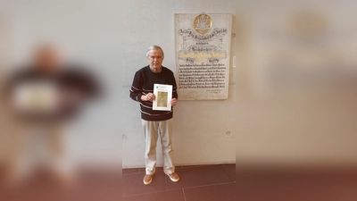 Karl-Heinz Zenker mit dem neuen Sammelblattband vor der Gedenkplatte des Freiherrn von Hallberg, die im Foyer des Rathauses hängt. (Foto: privat)