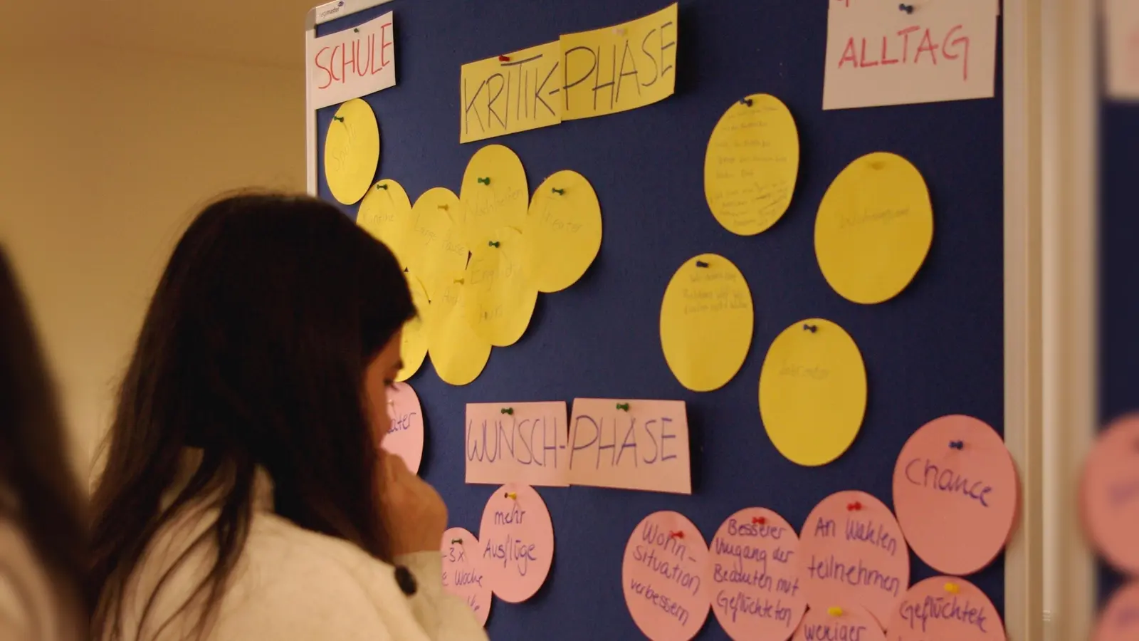 Eine Teilnehmerin vor einer Pinnwand mit Ideen, die im Demokratie-Workshop entstanden sind. (Foto: mehrWERT Demokratie)
