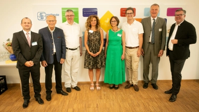 Oliver Jaschek (Geschäftsführer Helfende Hände gGmbH), Josef Mederer (Bezirkstagspräsident), Christian Müller (Stadtrat), Nariman Zimpel (Vorstandsvorsitzende Helfende Hände e.V.), Beate Bettenhausen (Vorständin Helfende Hände e.V.), Stephan Pilsinger (Bundestagsabgeordneter), Hubert Killer (Referatsleiter für Unterricht und Kultus) und Josef Schmid (Landtagsabgeordneter) bei der Eröffnungsfeier vor der Spenderwand.  (Foto: © Fabian Helmich/ Helfende Hände:)