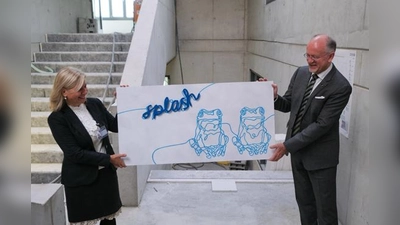 Drs. Rudolph Ensing (re.: Schuldirektor) und Dr. Alexia Giannakopoulou (li.: zukünftige Schuldirektorin der Grundschule) stellen das Design vor, das zukünftig die Treppenhäuser des Neubaus schmücken werden.  (Foto: Europäische Schule)