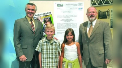 Horst Schneider (li.), Präsident der Landesverkehrswacht Bayern e.V. und Innenstaatssekretär Jürgen W. Heike zusammen mit zwei Schulkinder. (Foto: pi)