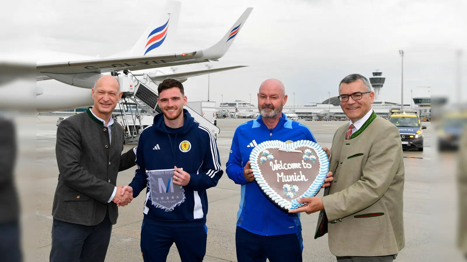 Jost Lammers, Vorsitzender der Geschäftsführung der Flughafen München GmbH, Teamcaptain Andy Robertson, Trainer Steve Clarke und Staatsminister Dr. Florian Herrmann (v.l.). (Foto:  Flughafen München GmbH)