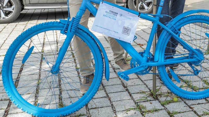 Für Kinderrechte: 1. Bürgermeister Christian Schiller (l.) und 3. Bürgermeister Wolfgang Schneider an dem knallblauen Rad vor dem Rathaus Herrsching. (Foto: Gemeinde)