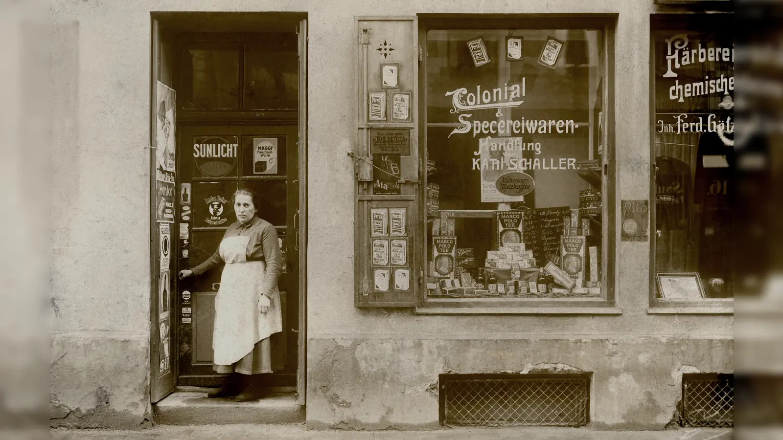 In der Colonial- &amp; Specereiwarenhandlung von Karl Schaller in der Westendstraße 17 konnten die Bürger sich mit dem versorgen, was man heute „Dinge des täglichen Bedarfs” nennt. Damals (das Bild wurde 1920 oder kurz darauf aufgenommen) wie heute sind die Menschen auf eine wohnortnahe Versorgung angewiesen. (Foto: Stadtarchiv München DE-1992-FS-PK-STB-13116)