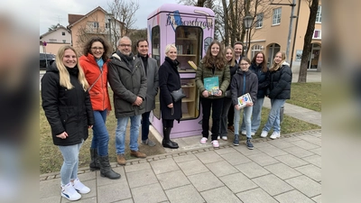 Über den neuen Bücherschrank in Aschheim freuen sich neben Vertreterinnen und Vertretern der Gemeinde auch die Schülerinnen der 8. Klasse des Kunstzweiges der St.-Emmeram-Realschule. (Foto: Gemeinde Aschheim)