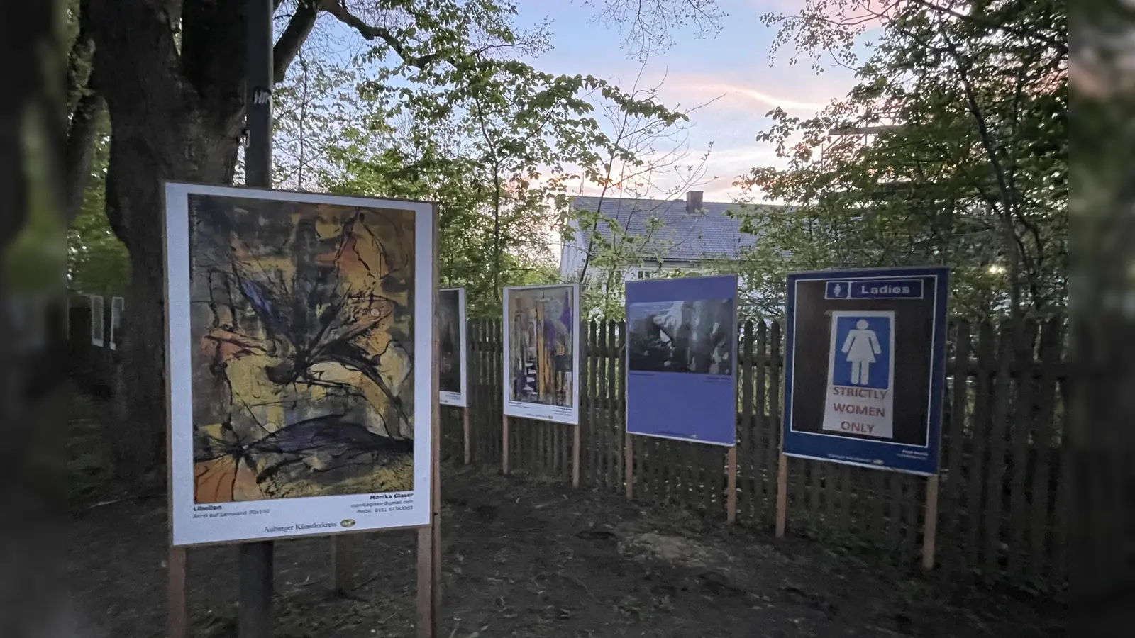 Idyllisch zwischen den großen Bäumen laden die Plakate zum Kunstgenuss ein. (Foto: pst)