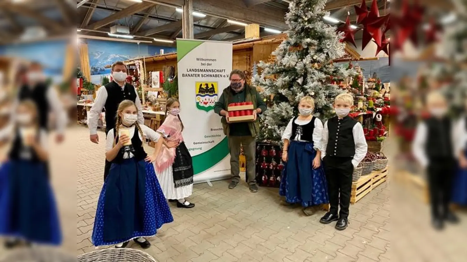 Kerzenübergabe: Carolina und Victoria von der Banater Kindertanzgruppe mit ihrem Leiter Harald Schlapansky (links),Thomas Gebert vom Daglfinger Blumenhof (mitte) und das Geschwisterpaar Hanna und Jonas (rechts). (Foto: privat)