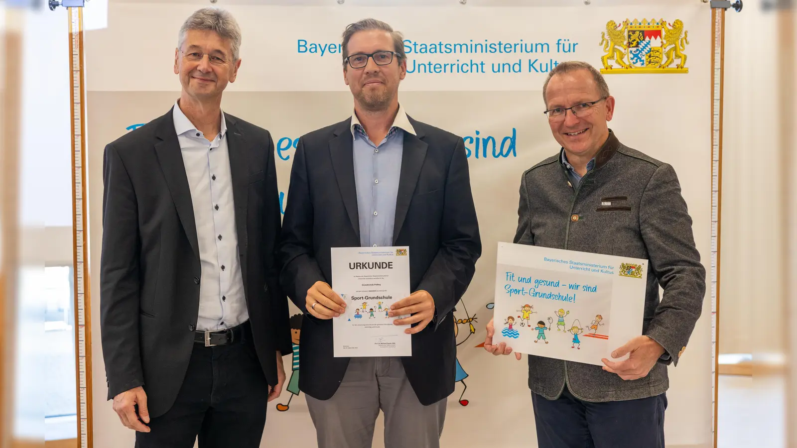 Kultusminister Michael Piazolo (links) und der Präsident des Bayerischen Landessportverbands (BLSV), Jörg Ammon, überreichten die Urkunde an Grundschulleiter Thomas Eusemann (Mitte). (Foto: Alexandra Beier)