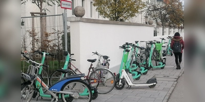 E-Scooter blockieren diese Feuerwehrzufahrt (links) an der Moosacher Straße und lassen für Passanten (rechts) kaum Platz auf dem Gehweg. Der Voi-Sprecher meint dazu: „Die Diskussion kommt zur falschen Zeit”. (Foto: job)