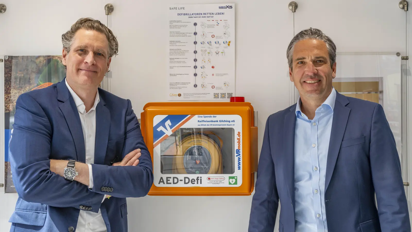 Die Vorstände der Raiffeisenbank Gilching eG, Jochen Beier und Oliver Glöggler (links), freuen sich sehr, dass Bürger mit dem Defibrillator für mögliche Notfälle noch besser gerüstet sind. (Foto: Raiffeisenbank Gilching eG)