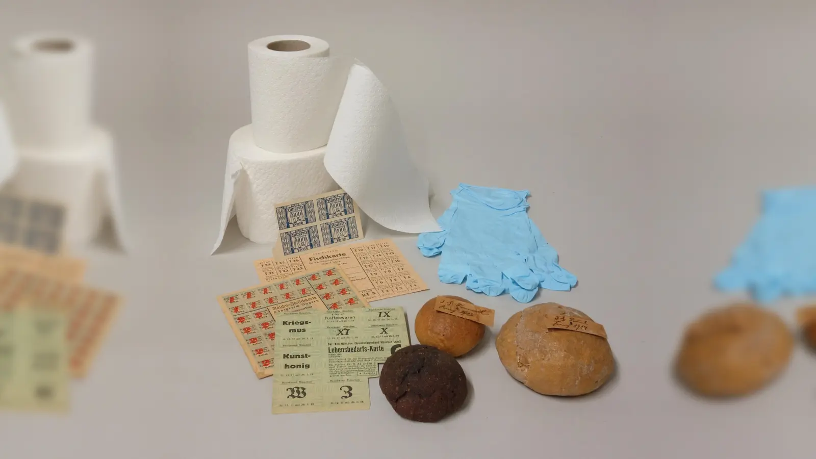 Kriegssemmeln und Lebensmittelkarten aus den Weltkriegen sowie begehrte Ware in der Corona-Krise: Toilettenpapier und Schutzhandschuhe.  (Foto: Museum Erding)