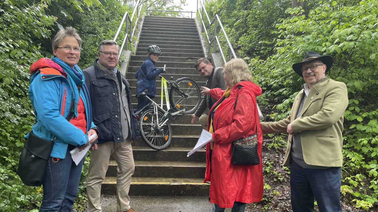 Jeden Tag schleppt der Sohn von Kathrin Gobitz-Pfeifer (li.) sein Radl über die Treppe. Die Pläne für einen „Durchstich” für einen Rad- und Fußweg stellten (v. r.) Manfred Spannagl (CSU), CSU-Bezirksrätin Barbara Kuhn, Sebastian Kriesel (BA-Vorsitz) auf der Stadtteiltour Landtagsabgeordnetem Josef Schmid (2.v.l.) vor. (Foto: Patrizia Steipe)