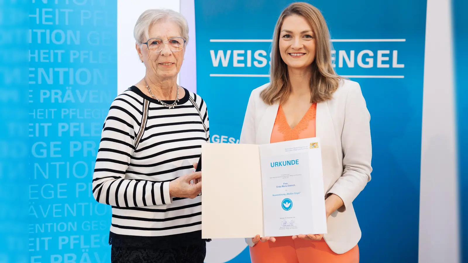 Erika Dietrich (links) aus Kirchheim erhielt die Urkunde „Weißer Engel” von Bayerns Staatsministerin für Gesundheit, Pflege und Prävention, Judith Gerlach. (Foto: StMGP)