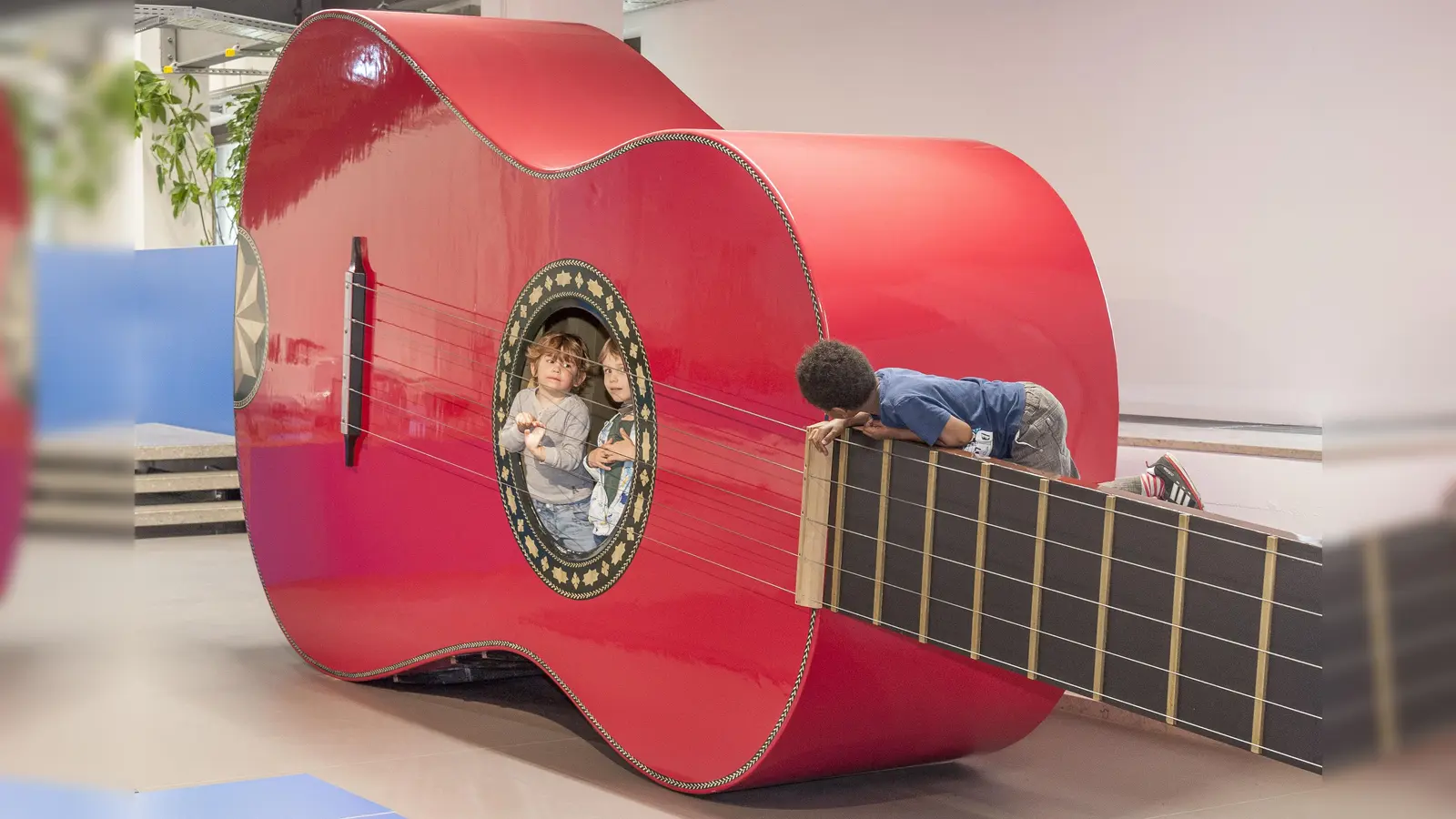 Das Kinderreich im Deutschen Museum: In der roten Riesengitarre kann man erleben, wie es sich anfühlt, wenn draußen jemand an den Saiten zupft. (Foto: Deutsches Museum)