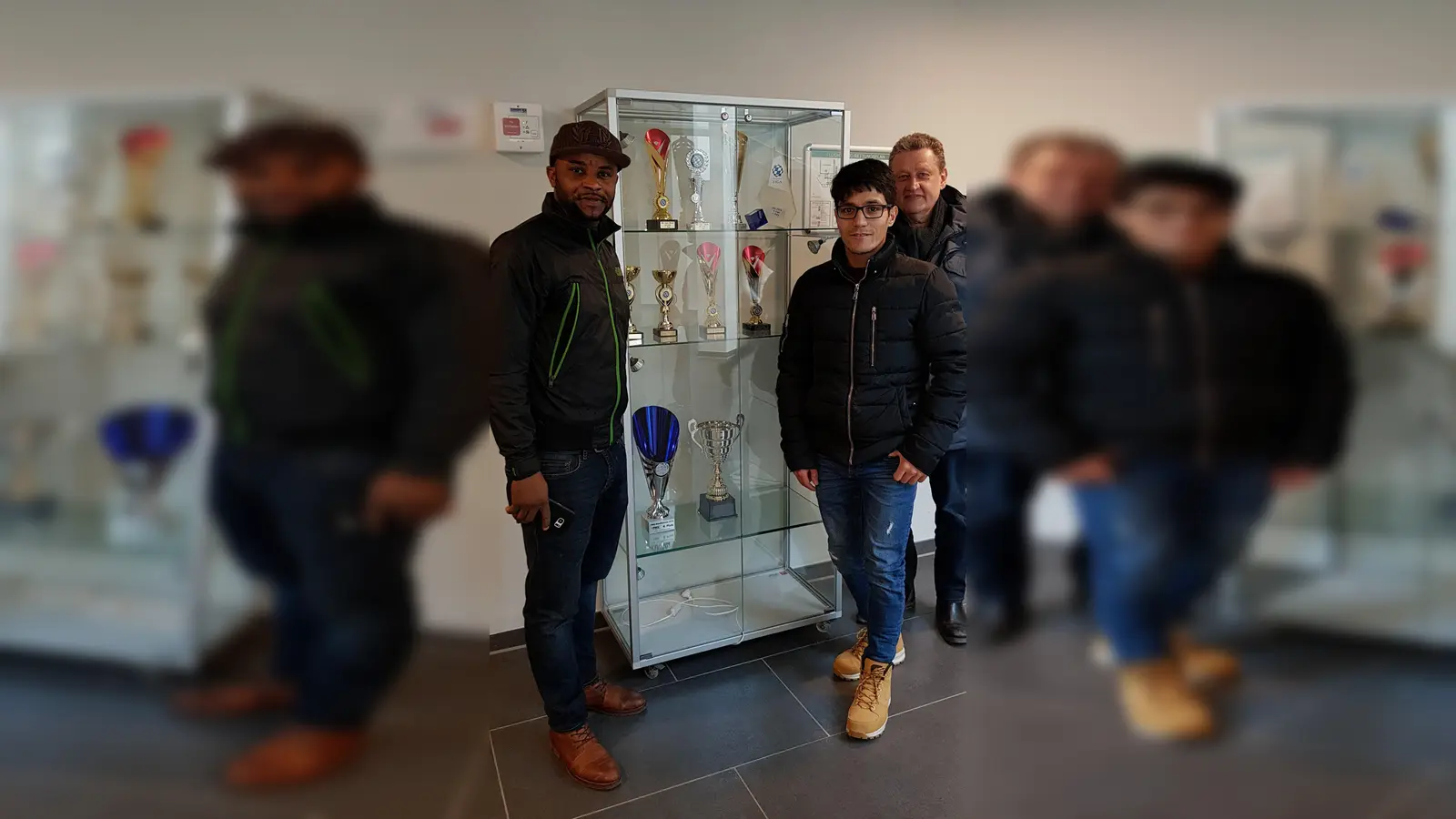 Thomas Weingärtner (hinten rechts) und die Sport-Asse Norridin und Patrick freuen sich über die Vitrine für ihre sportlichen Auszeichnungen. (Foto: Helferkreis)