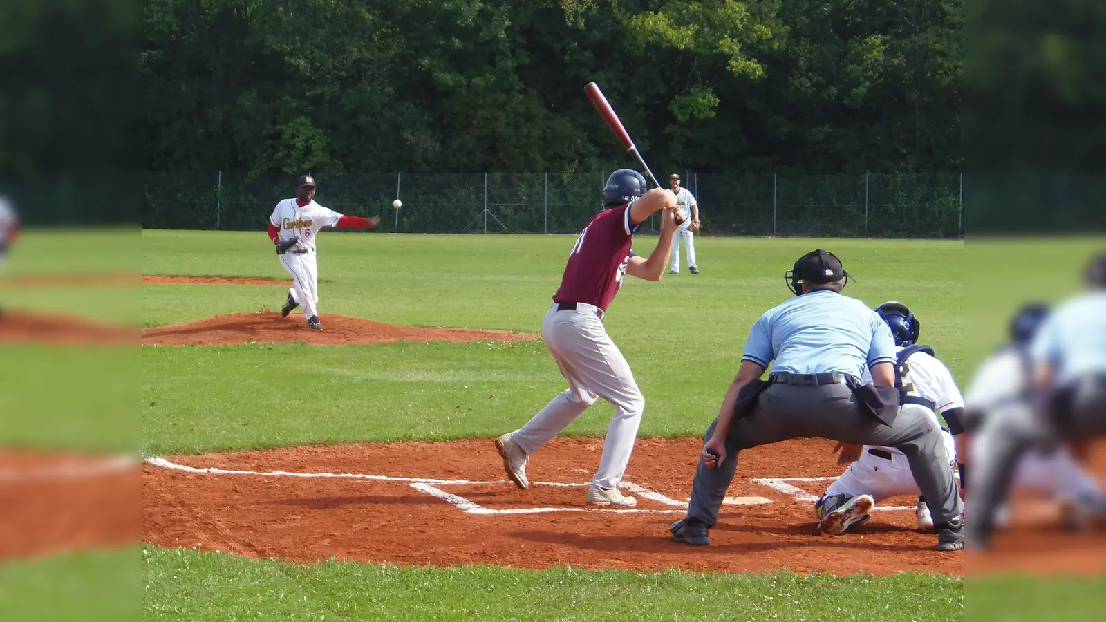 Caribes Werfer Esahu Tejada wirft den Ball zu einem Tübingen Hawks Schlagmann im ersten Spiel gegen Tübingen. Im Hintergrund schaut Innenverteidiger Jakob von Mosch gebannt zu. (Foto: Verein)