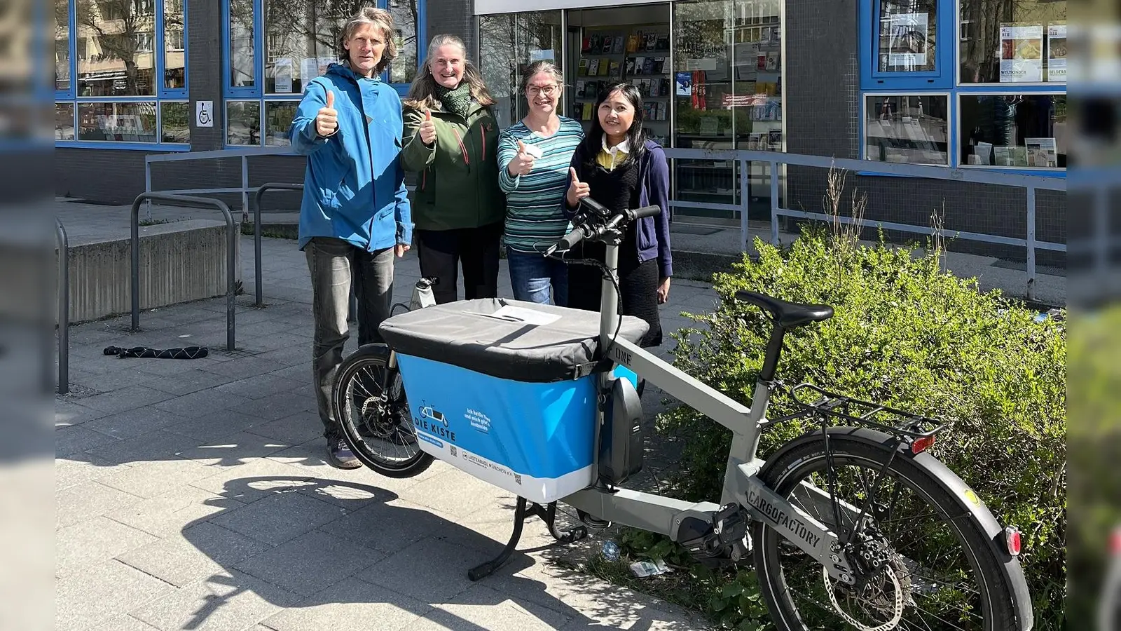 V.l.: Patrick Kleinknecht vom „Verein Freies Lastenradl”, die Initiatorin der Aktion, Marion Galler (ÖDP), und die Bibliotheksangestellte Gabriele Holocher mit Kollegin stellen das kostenlose Lastenrad „Theo” vor. (Foto: Marion Galler)