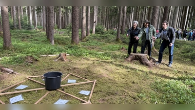 Försterin Christine Achhammer, Revierleiter Harald Appelt und Landrat Stefan Frey (v.l.) probieren das Zapfenweitwerfen. (Foto: pst)