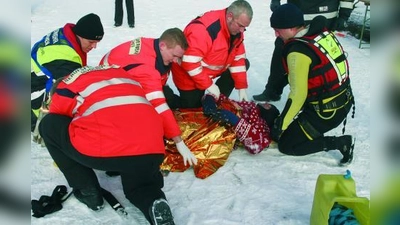 Die Rettungssanitäter versorgen die eingebrochene Person am Ufer und haben sie in eine Rettungsdecke gewickelt. (Foto: cm)