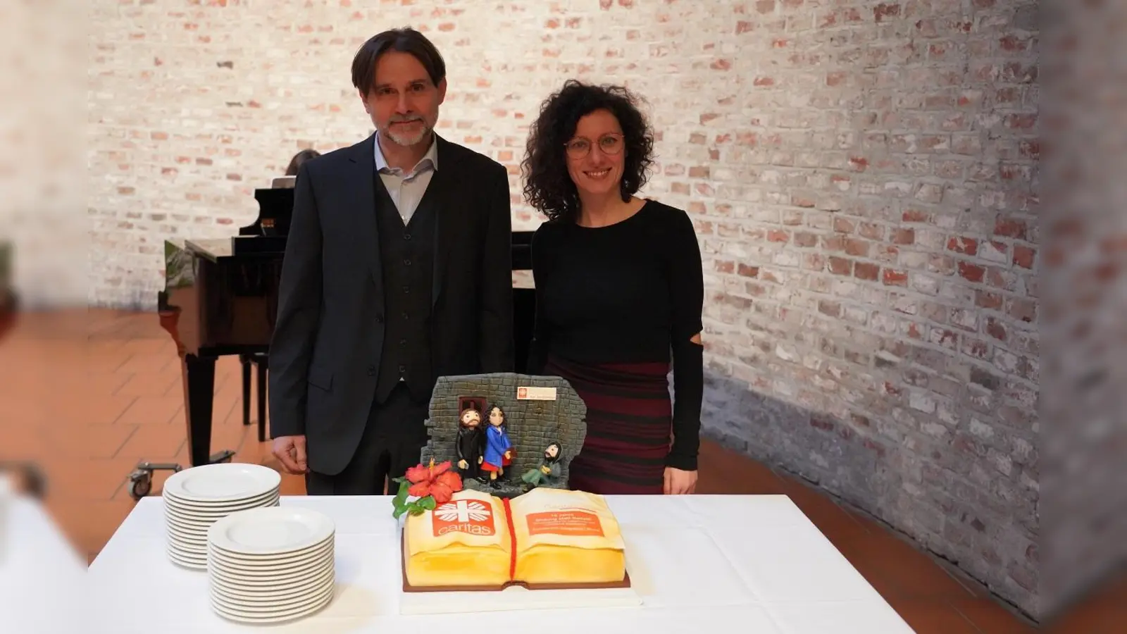 Mit einer originellen Jubiläumstorte wurden die beiden Caritas-Streetworker Nedialko Kalinov und Ramona Sisu zum zehnjährigen Bestehen des Projekts „Bildung statt Betteln“ überrascht. (Foto: Caritas München / Bäumlisberger)