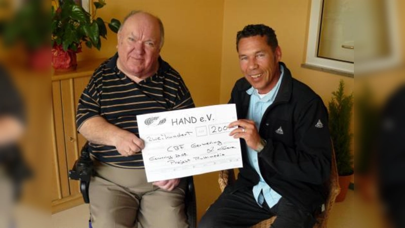 Spenden hat der neugegründete Germeringer Verein „HAND e.V.“ bei einem Benefizkonzert gesammelt. Hier übergibt der Vereinsvorsitzende Ado Greve (l.) den Erlös an Hermann Sickinger für das „Projekt Multimedia“. (Foto: pi)
