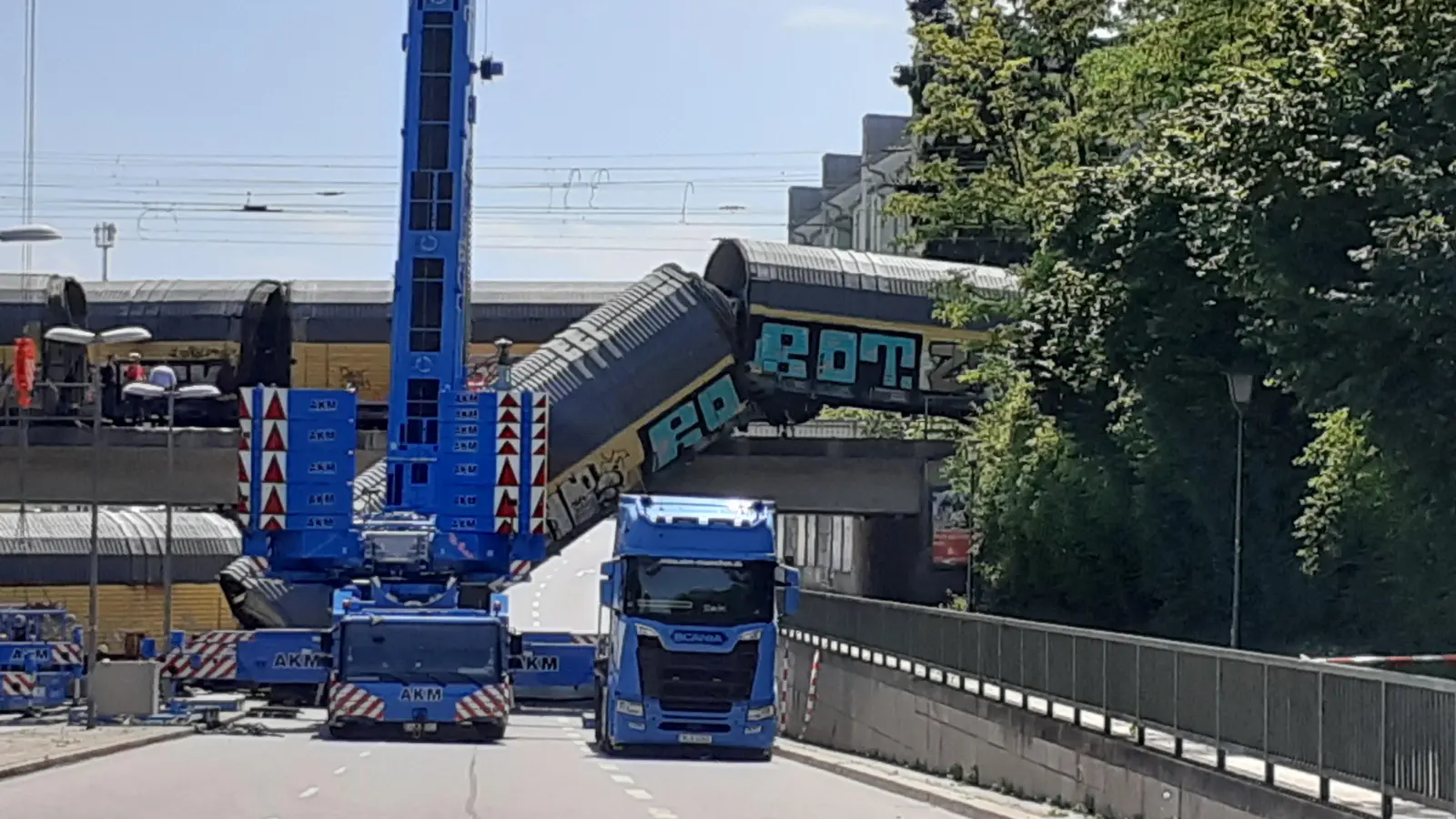 Einer der Waggons (links) wurde nach dem Sturz zunächst auf die Straße gezogen, um danach in stundenlanger aufwändiger Bergungsarbeit von Schwerlastkränen wieder aufs Gleis gestellt zu werden.  (Foto: mha)