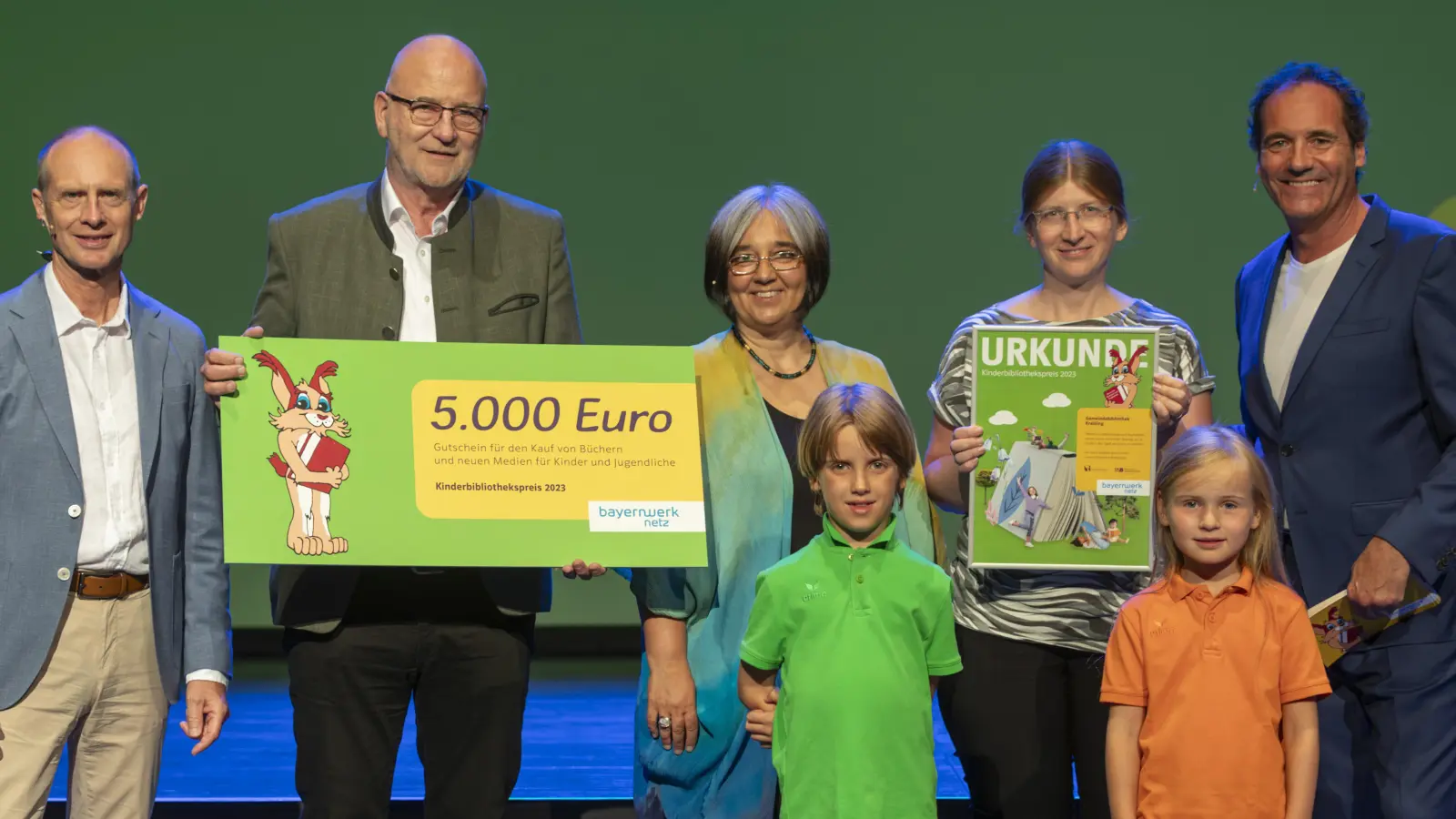 Freuten sich über die Auszeichnung (von links): Bayernwerk-Chef Dr. Egon Leo Westphal, Rudolph Haux (Bürgermeister Krailling), Ministerialrätin Dr. Elisabeth Donoughue, Diana Widmann (Leiterin der Gemeindebibliothek Krailling), Moderator Thomas Ohrner sowie die beiden Bühnenkinder David und Anna. (Foto: altrofoto/Bayernwerk AG)