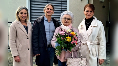 100. Fernwärmeanschluss: Sabine Abtmeier und Jan Haas (Gemeindewerke Gilching) gratulieren Magdalena und Katrin Laternser mit einem Blumenstrauß (v.l.). (Foto: Gemeindewerke Gilching)