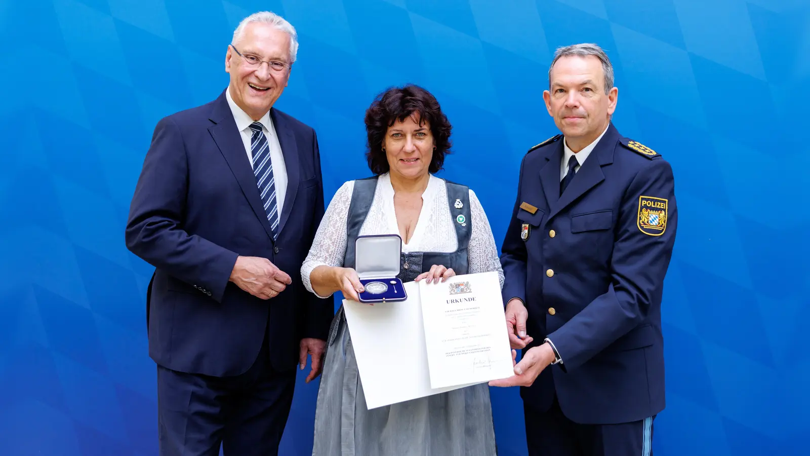 Innenminister Joachim Herrmann (links) und Landespolizeipräsident Michael Schwald (rechts) ehrten Michaela Wagner aus Gauting. Sie bewahrte einen 92-jährigen Mann davor, einem Betrüger eine hohe Geldsumme zu übergeben. Der Betrüger wurde inzwischen zu einer fünfjährigen Haftstrafe verurteilt. (Foto: Matthias Balk/Bayerisches Staatsministerium des Innern, für Sport und Integration)
