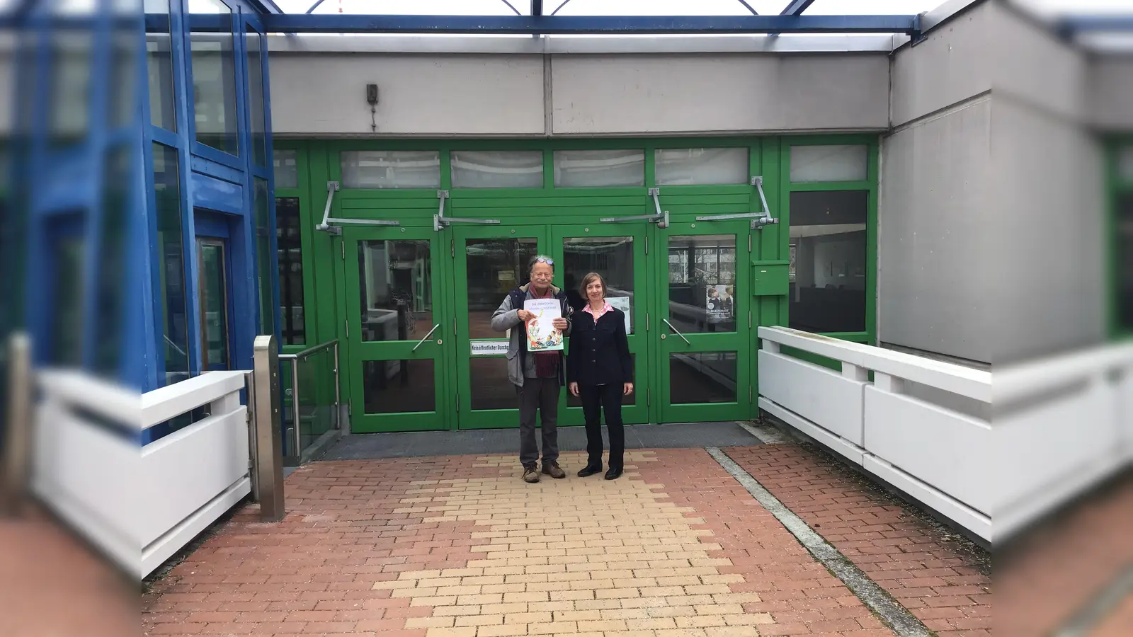 Links im Bild der Lesefuchs Peter Schönwälder und rechts die Rektorin der Nadischule Elke Kandlbinder, in der die Lesefüchse normalerweise vorlesen. Ab sofort aber nur noch online. (Foto: Daniel Mielcarek)