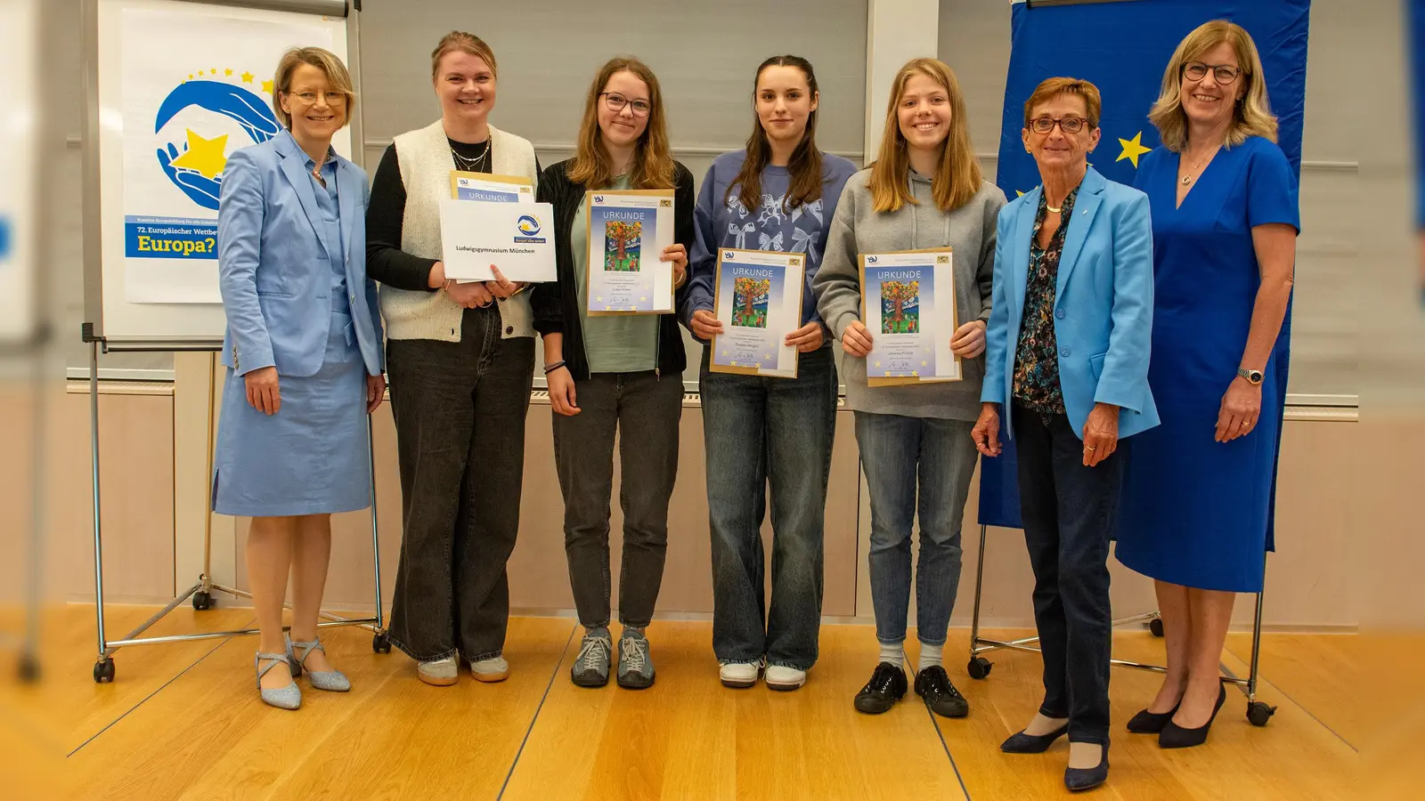 Alexandra Böhm (Europäischer Wettbewerb – Landesbeauftragte Bayern, rechts), die weitere stv. Bezirkstagspräsidentin Friederike Steinberger (Zweite von rechts) und Anne Radlinger (Regierung von Oberbayern, links) zeichneten das Ludwigsgymnasium München aus. (Foto: Bezirk Oberbayern / Jennifer Sandmeyer)