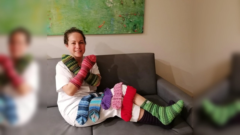 Viviana Dasch, Gesundheits- und Krankenpflegerin der Palliativstation, zeigt die Bettsocken für Patienten, die ihre Kollegin Birgit Berthold gestrickt hat. (F.: Kreisklinik Ebersberg)