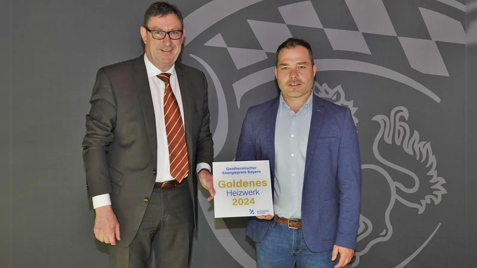 Landrat Martin Bayerstorfer und Michael Perzl, Geschäftsführer des Zweckverbands Geowärme Erding, mit der Auszeichnung „Goldenes Heizwerk 2024“ (Foto: LRA Erding)